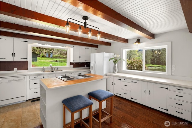 kitchen with beam ceiling, white cabinetry, white appliances, and a sink