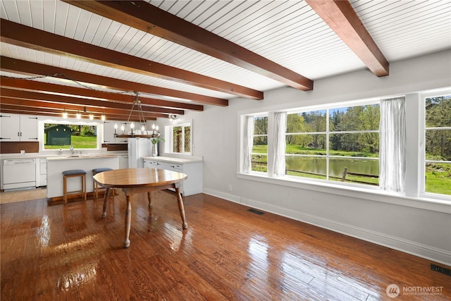 dining room featuring beamed ceiling, plenty of natural light, visible vents, and baseboards