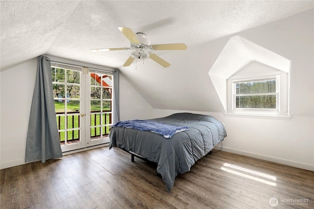 bedroom featuring wood finished floors, access to exterior, baseboards, a textured ceiling, and lofted ceiling