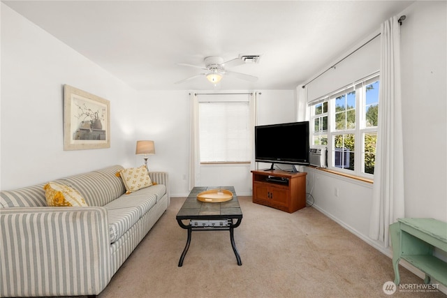 living room featuring a ceiling fan, visible vents, light colored carpet, and baseboards