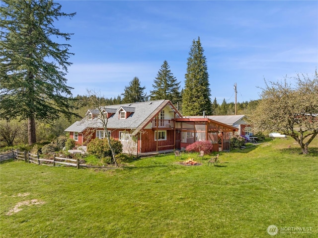 rear view of house featuring a lawn, fence, and a sunroom