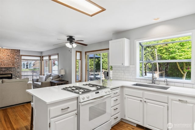 327 Keach Ct, Steilacoom, WA 98388 - kitchen featuring white gas range oven, a sink, a peninsula, and plenty of natural light