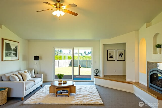 carpeted living room with baseboards, a glass covered fireplace, and ceiling fan