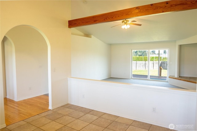 unfurnished room with lofted ceiling with beams, arched walkways, ceiling fan, and light tile patterned flooring
