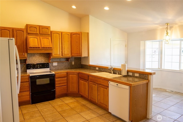 kitchen featuring a peninsula, a sink, vaulted ceiling, white appliances, and tile countertops