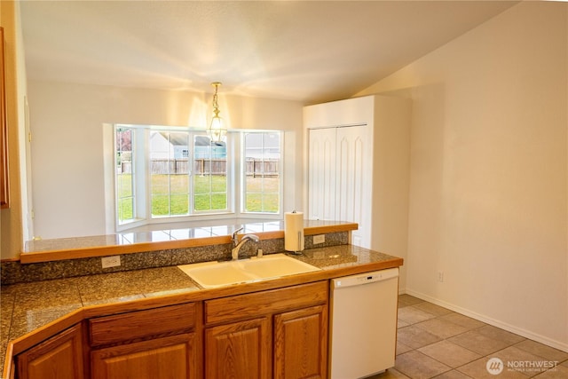 kitchen featuring white dishwasher, tile counters, brown cabinetry, and a sink