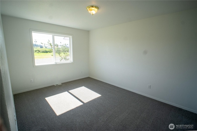 spare room featuring dark colored carpet and baseboards