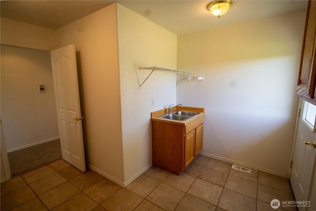 laundry area with baseboards, visible vents, a sink, and light tile patterned floors