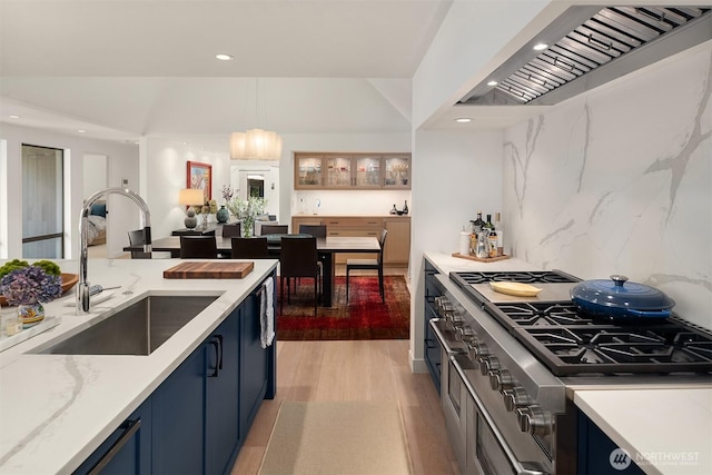 kitchen featuring premium range hood, a sink, blue cabinets, range with two ovens, and recessed lighting
