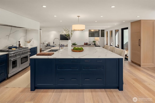 kitchen featuring a sink, double oven range, light wood-type flooring, recessed lighting, and blue cabinets