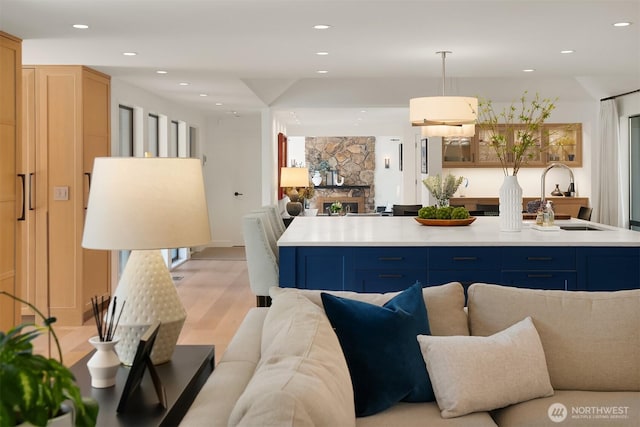 kitchen featuring open floor plan, a sink, blue cabinetry, light wood-style floors, and recessed lighting