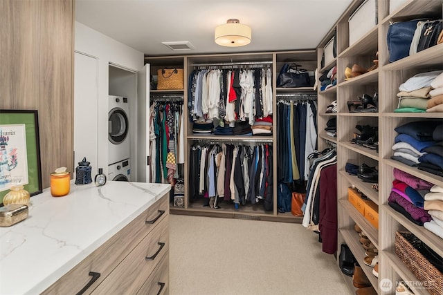 walk in closet with stacked washer and clothes dryer and carpet