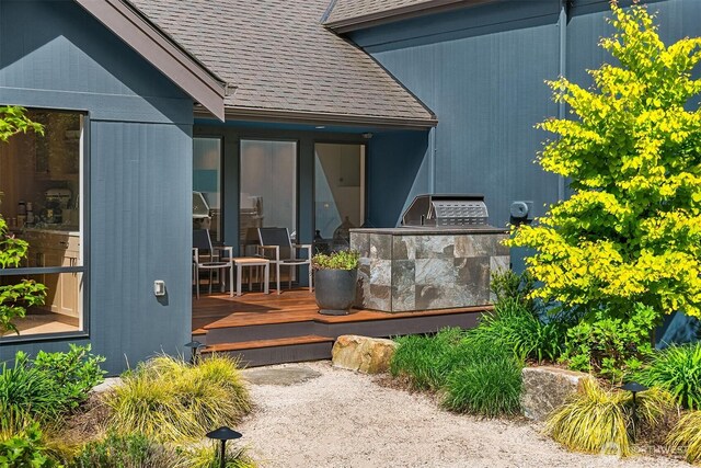 property entrance with area for grilling, a wooden deck, and a shingled roof