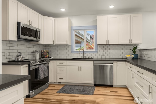 119 37th Ave E, Seattle, WA 98112 - kitchen featuring dark countertops, a sink, white cabinets, backsplash, and appliances with stainless steel finishes