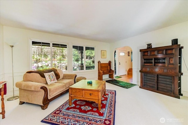 carpeted living area featuring arched walkways