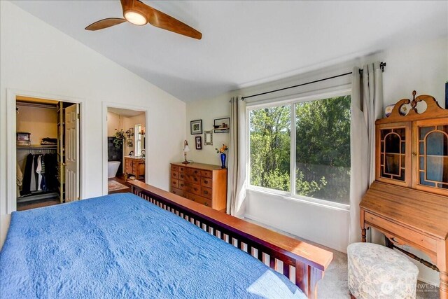 bedroom with vaulted ceiling, a closet, a spacious closet, ceiling fan, and ensuite bath