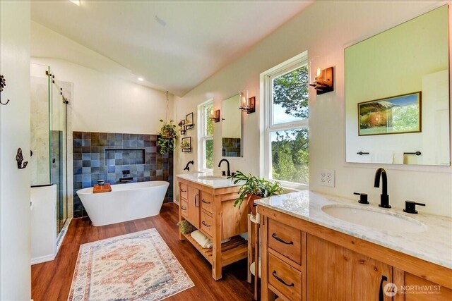 full bath featuring a tiled fireplace, wood finished floors, a sink, and a stall shower