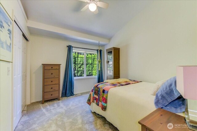 bedroom featuring vaulted ceiling, a closet, baseboards, light colored carpet, and ceiling fan