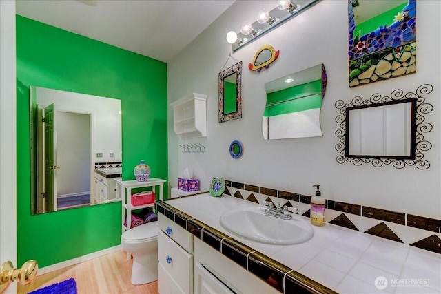 bathroom featuring wood finished floors, toilet, and vanity