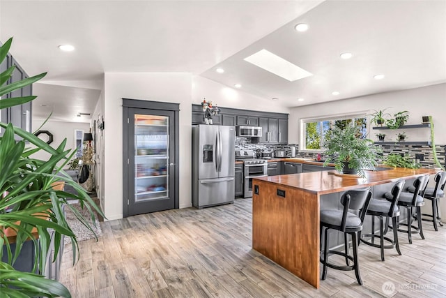 4353 Gooding Ave, Bellingham, WA 98226 - kitchen with decorative backsplash, appliances with stainless steel finishes, a peninsula, wood counters, and a breakfast bar