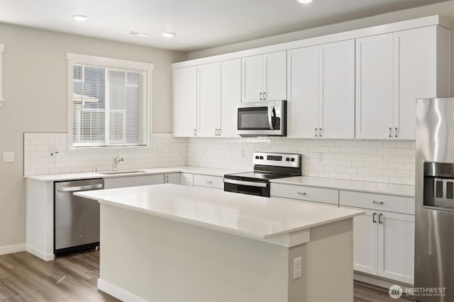 kitchen with stainless steel appliances, a center island, a sink, and wood finished floors
