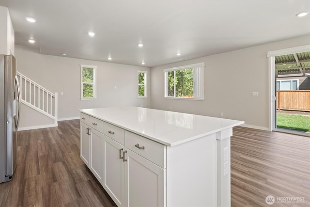 kitchen with baseboards, dark wood-style flooring, a kitchen island, and stainless steel refrigerator with ice dispenser