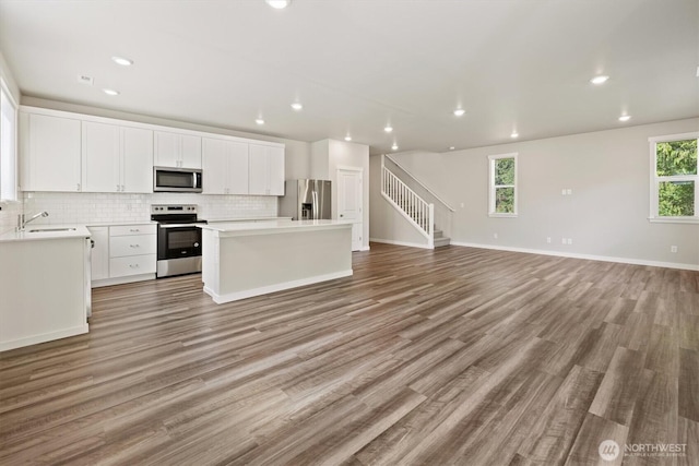 kitchen featuring light wood-style flooring, a center island, stainless steel appliances, open floor plan, and tasteful backsplash