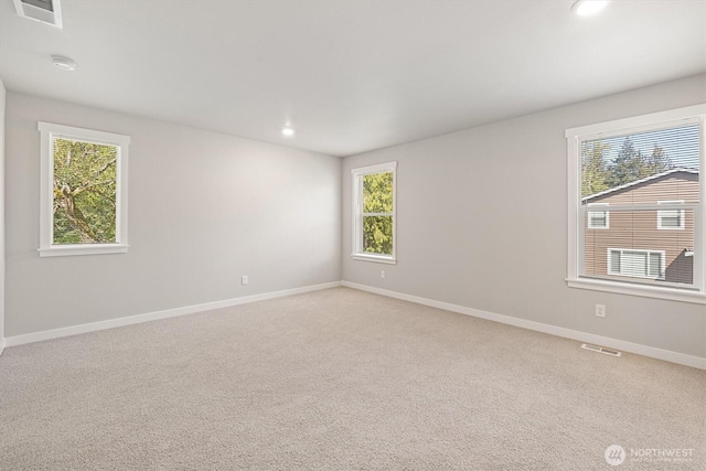 unfurnished room featuring baseboards, visible vents, and a healthy amount of sunlight