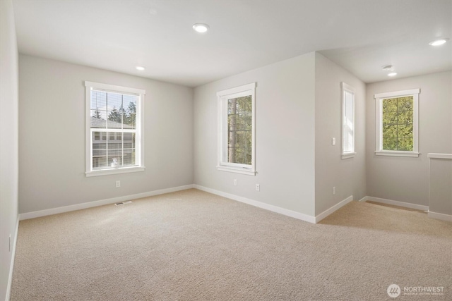 unfurnished room with a healthy amount of sunlight, baseboards, and light colored carpet
