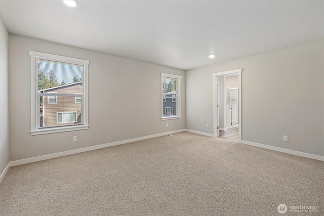 empty room featuring recessed lighting, baseboards, light colored carpet, and a wealth of natural light