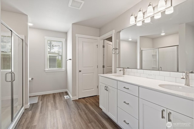 full bathroom featuring a stall shower, visible vents, a sink, and wood finished floors