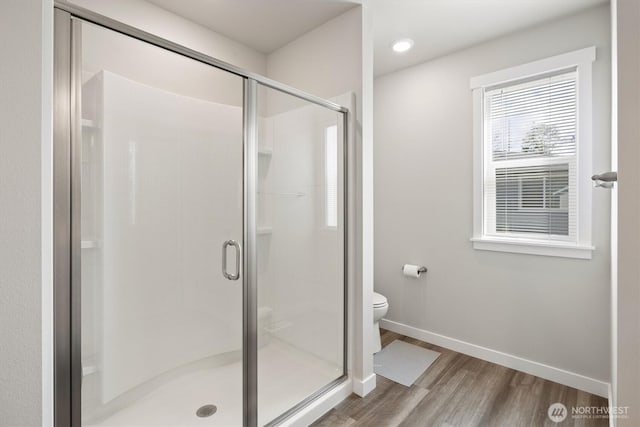 bathroom featuring baseboards, a stall shower, toilet, and wood finished floors