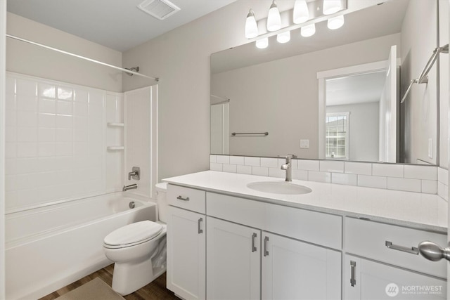 bathroom with vanity, toilet, wood finished floors, tasteful backsplash, and visible vents