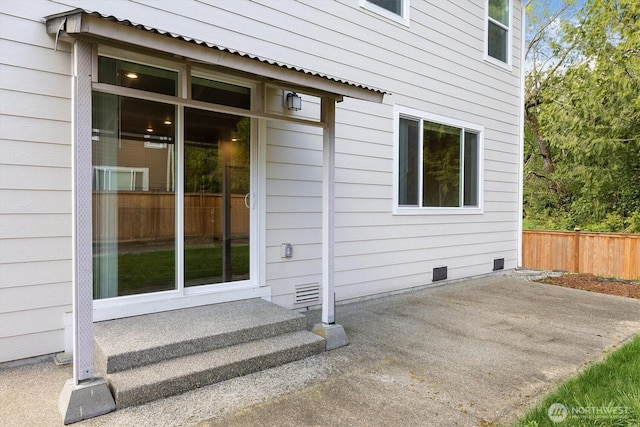 property entrance with a patio area, fence, and crawl space