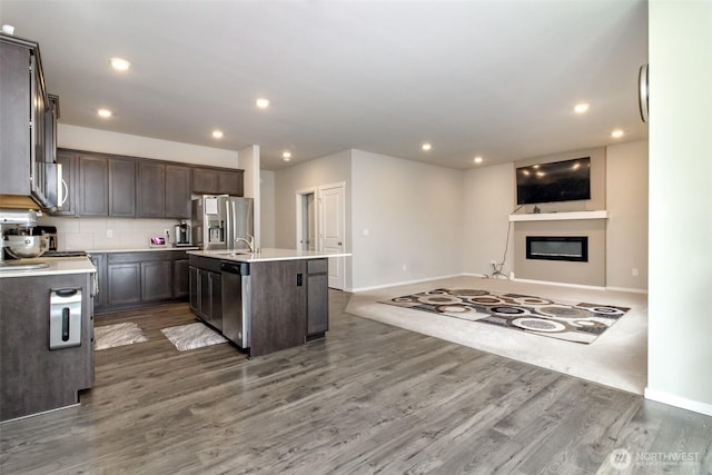 19825 152nd Street Ct SE, Bonney Lake, WA 98391 - kitchen featuring stainless steel appliances, wood finished floors, dark brown cabinetry, baseboards, and a kitchen island with sink