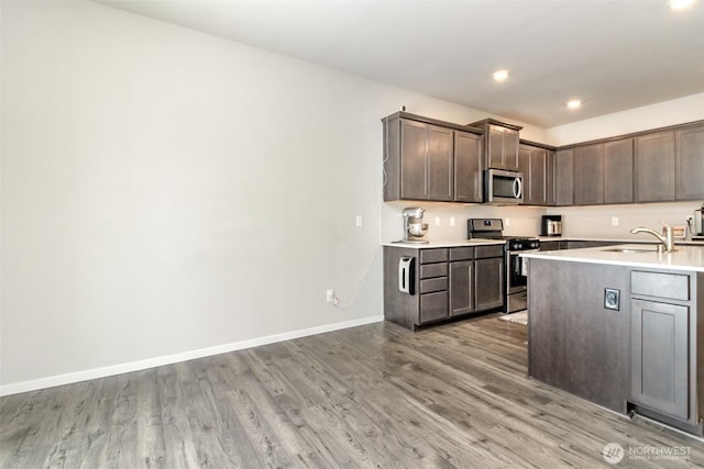 19825 152nd Street Ct SE, Bonney Lake, WA 98391 - kitchen with light countertops, a sink, light wood-style floors, dark brown cabinetry, and appliances with stainless steel finishes