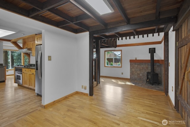 unfurnished living room featuring a wood stove, wooden ceiling, beamed ceiling, baseboards, and light wood-style flooring