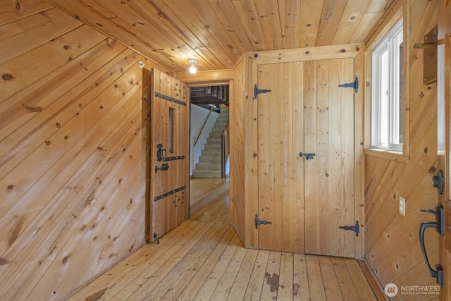 interior space with hardwood / wood-style flooring, wood walls, wooden ceiling, and stairway