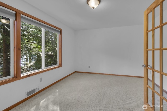 spare room featuring baseboards, visible vents, and carpet