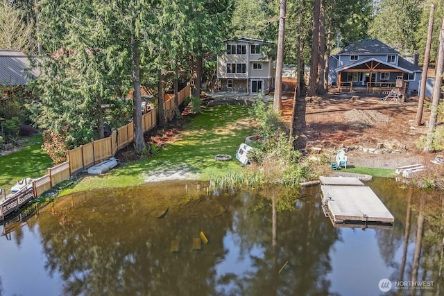 dock area with fence, a lawn, and a water view