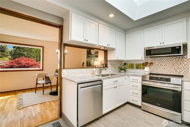 kitchen with light wood-style floors, recessed lighting, white cabinetry, a sink, and stainless steel appliances