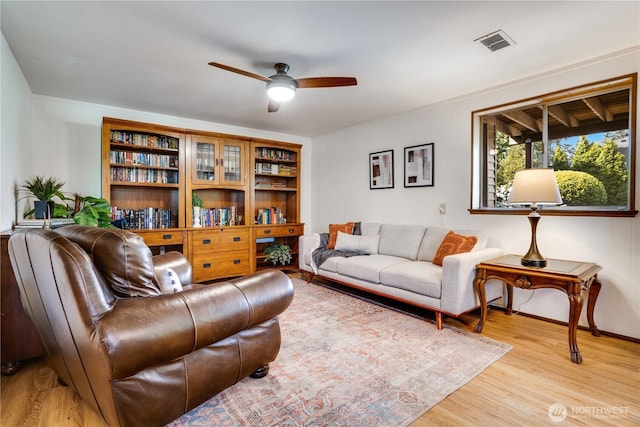 living area with a ceiling fan, baseboards, visible vents, and light wood-style floors
