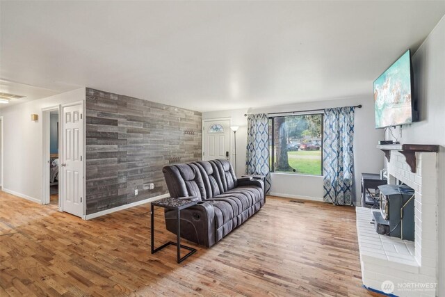 living room featuring baseboards, an accent wall, wood finished floors, and visible vents