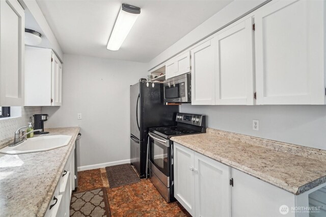 kitchen with a sink, light countertops, stainless steel appliances, and white cabinetry