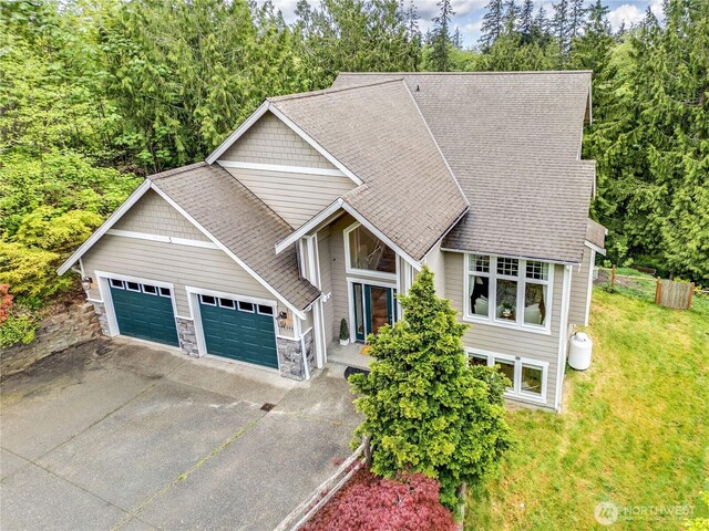 view of front of property with a garage, driveway, a front lawn, and stone siding
