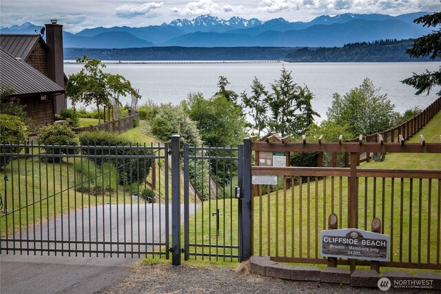 view of gate featuring fence, a yard, and a water and mountain view