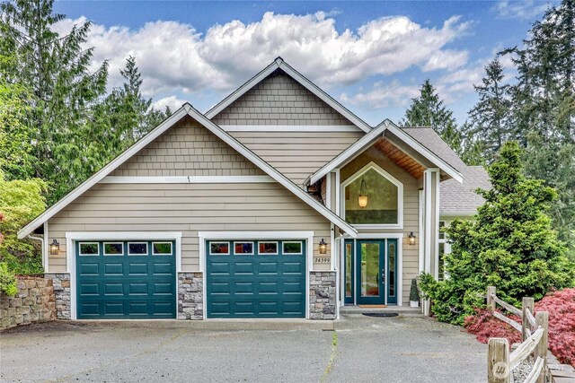craftsman-style home featuring aphalt driveway, stone siding, and a garage