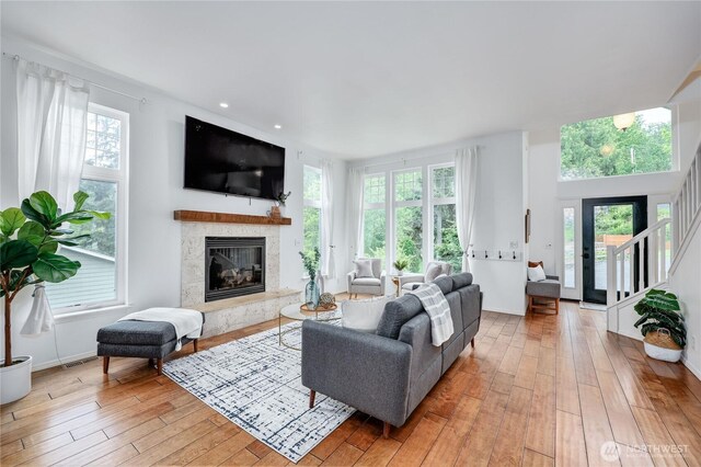 living room with a fireplace, visible vents, a wealth of natural light, and light wood-type flooring