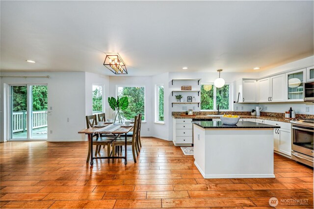 kitchen featuring dark countertops, stainless steel range, open shelves, and white cabinets