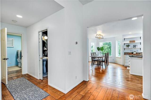 hall featuring separate washer and dryer, baseboards, recessed lighting, and light wood-style floors